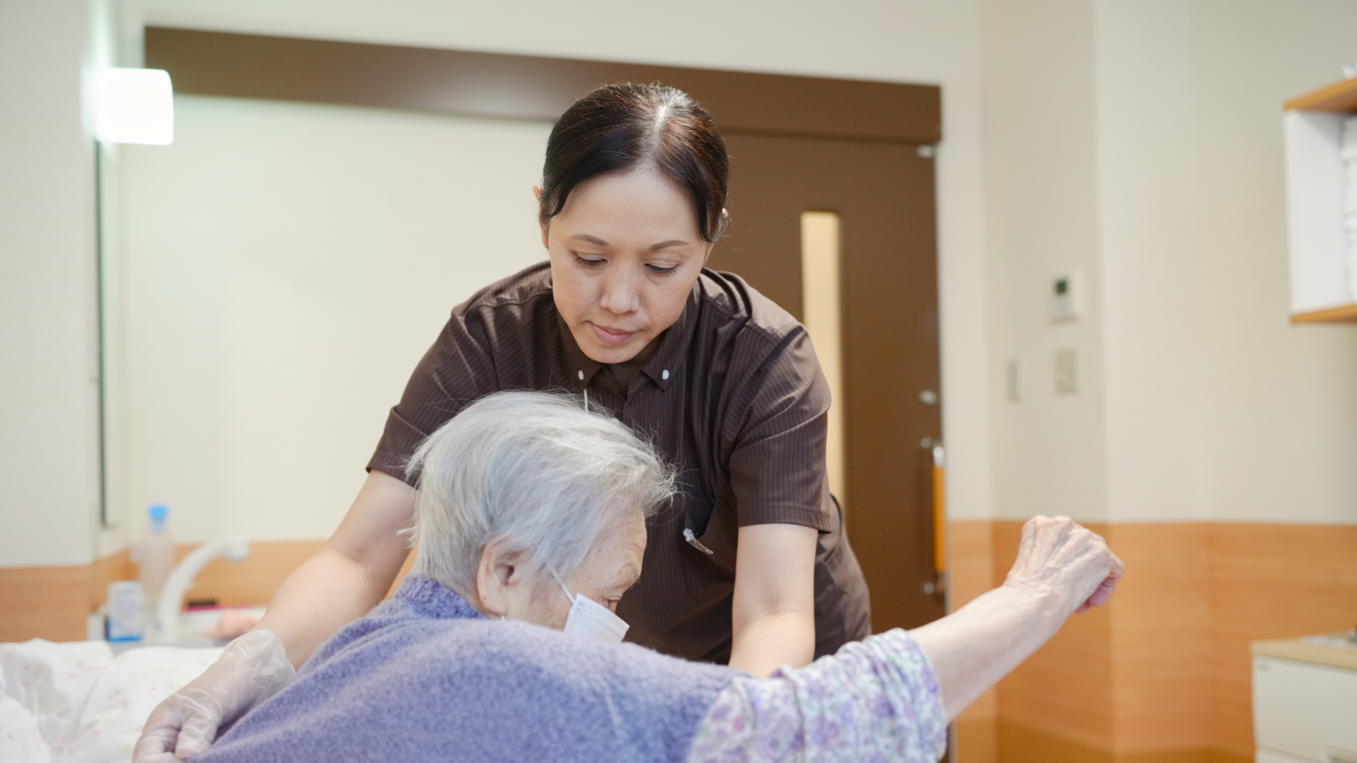 更衣の介助をする女性介護士