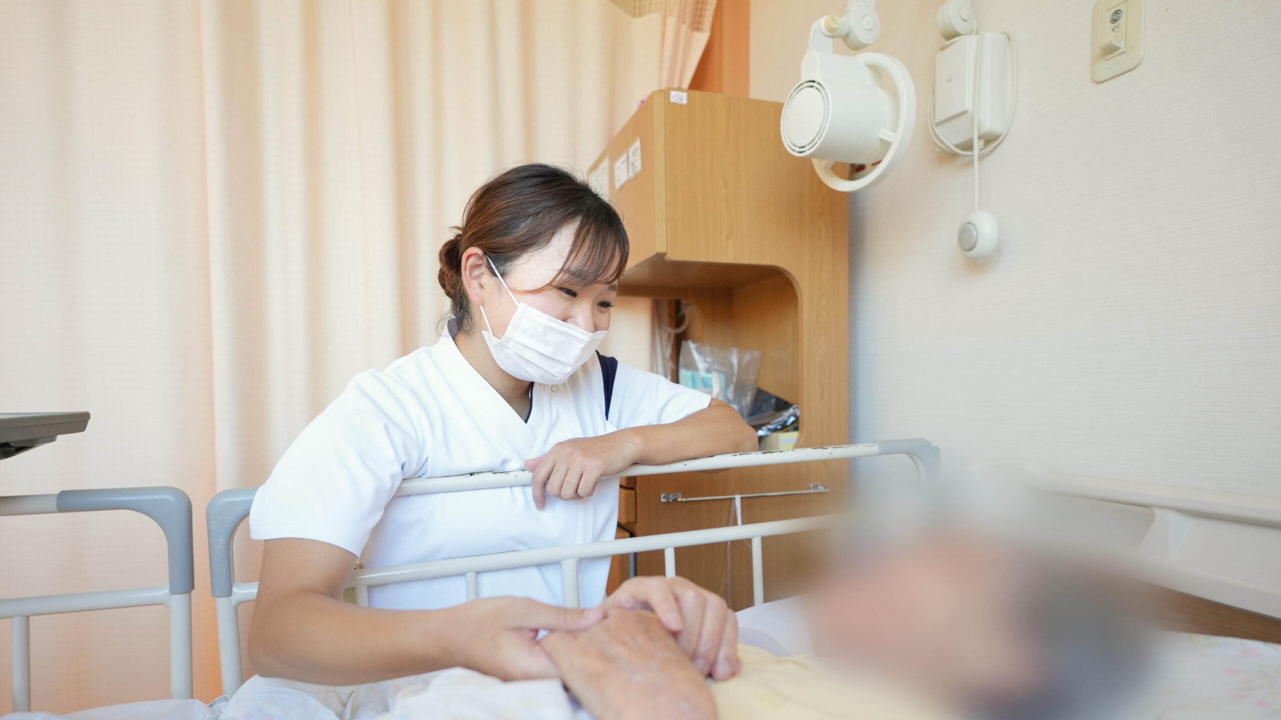 患者の手を握る女性看護師